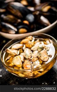 Pickled mussels in a glass bowl with spices. On a black background. High quality photo. Pickled mussels in a glass bowl with spices.