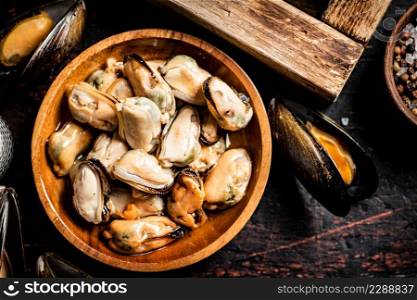 Pickled mussels in a wooden plate on the table. Against a dark background. High quality photo. Pickled mussels in a wooden plate on the table.