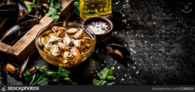 Pickled mussels with parsley and spices on the table. On a black background. High quality photo. Pickled mussels with parsley and spices on the table.