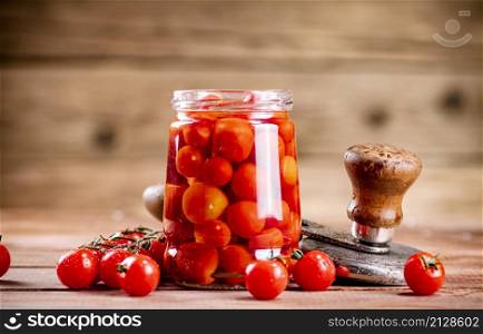 Pickled ripe tomatoes in a glass jar. On a wooden background. High quality photo. Pickled ripe tomatoes in a glass jar.