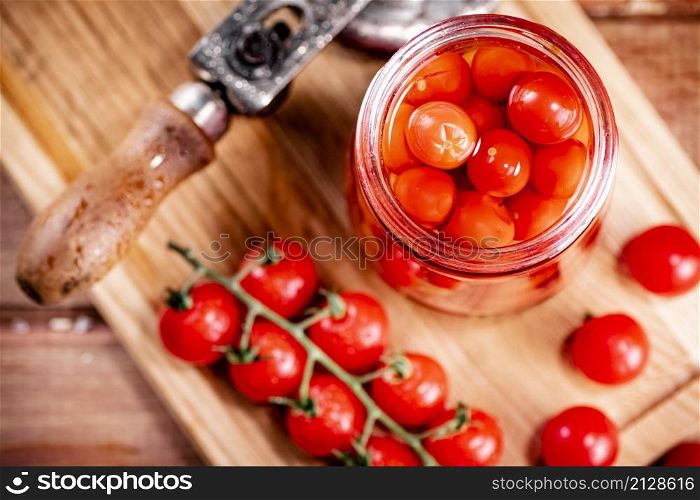 Pickled ripe tomatoes in a glass jar. On a wooden background. High quality photo. Pickled ripe tomatoes in a glass jar.