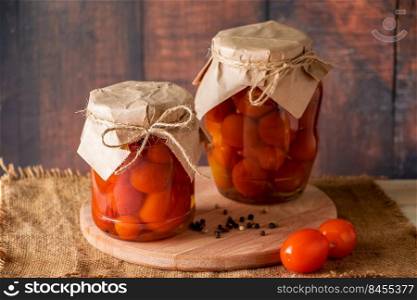 Pickled tomatoes in a glass jar on wooden background. Fermented trending food. Home rustic style.. Pickled tomatoes in glass jar on wooden background. Fermented trending food. Home rustic style.