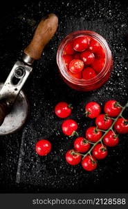 Pickled tomatoes in a jar on a stone board. On a black background. High quality photo. Pickled tomatoes in a jar on a stone board.