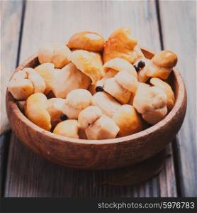 Pickled white boletus with black pepper and bay leaf in a wooden bowl. Pickled white boletus