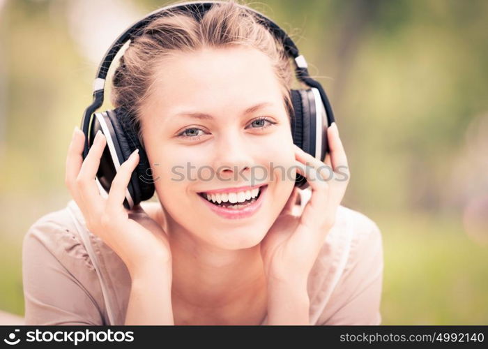 Picnic at summer park. Young attractive girl in summer park wearing headphones