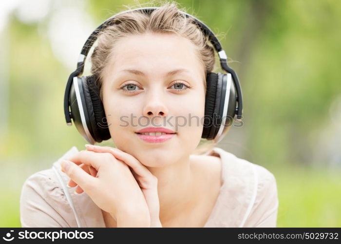 Picnic at summer park. Young attractive girl in summer park wearing headphones