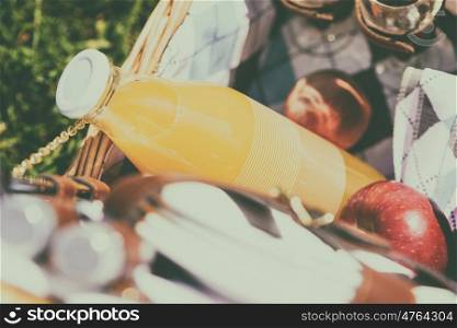 Picnic Basket With Orange Juice Bottle, Apples, Peaches, Oranges And Croissants On Green Grass In Spring
