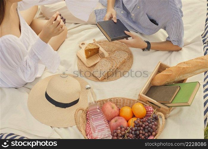 picnic concept The lovers who dress in white and blue smiling to each other while being on the picnic in the natural setting.