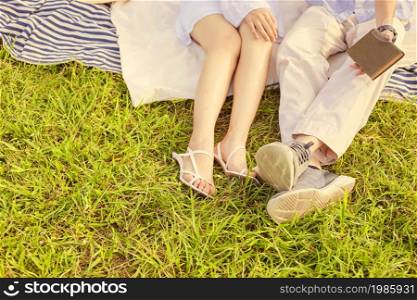 picnic concept The woman with white skirt and sandals sitting beside the man who puts on beige pants and grey sneakers.