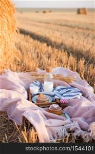 picnic in a wheat field near Round Bales. milk and cinnamon rolls