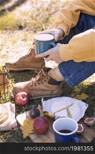 picnic in the woods. hiking boots, cup in hand, brie cheese, apples, figs