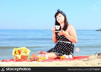Picnic. Retro woman drinking coffee on the beach.