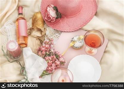 Picnic scene with rose wine, champagne glass, flowers, sun hat, cheese and baguette, candle and flowers. Romantic date idea with food and drink in summer. Top view. Empty label mock-up