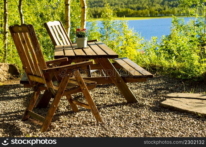 Picnic site rest stop area wooden chairs and table with flowers decoration on norwegian lake fjord shore. Holidays relaxation on trip. Scandinavia Europe.. Rest stop area picnic site on fjord lake shore