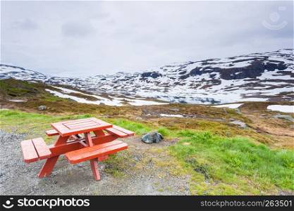 Picnic site wooden table and benches witn view at norwegian snowy mountains and lake, Scandynavia Europe.. Camp site with picnic table in norwegian mountains