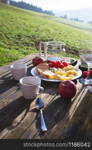 Picnicin on a farm. morning in the mountains. cheeses, baguette, tomatoes, avocado, coffee on a wooden table