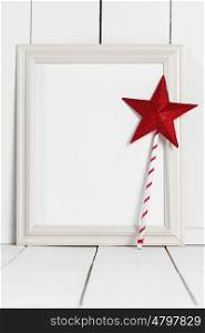 Picture frame and magic wand. Vintage white wooden picture frame with blank white copy space and red star magic wand