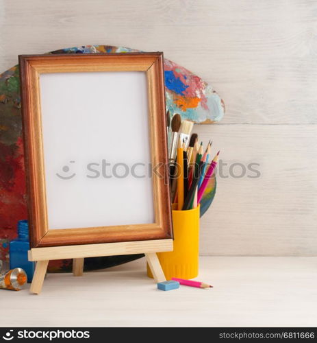 picture frame and paints on wooden background