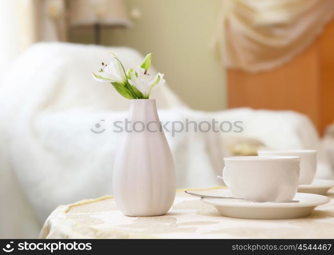 picture of a coffe table with cup and flower on it