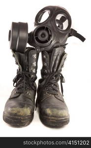 Picture of a couple of dirty old used millitary boots and a gasmask