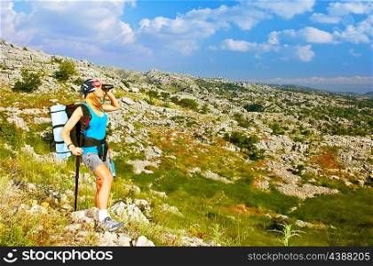 Picture of active hiker girl with big backpack standing on the top of mountain, beautiful mountains landscape, extreme climbing sport, traveling woman looking in binocular, journey adventure