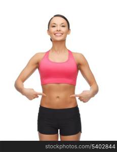 picture of beautiful sporty woman pointing at her six pack