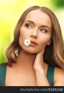 picture of beautiful woman with camomile in mouth