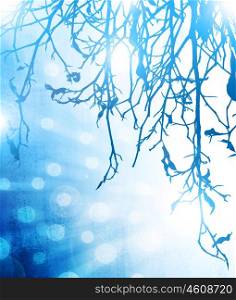 Picture of blue abstract winter background, frozen tree branch and bright blur light, forest in hoarfrost on glowing lights backdrop, christmas holiday postcard, glowing snowflakes in snowy woods