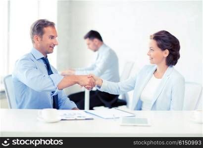 picture of businessman and businesswoman shaking hands in office. man and woman shaking hands in office