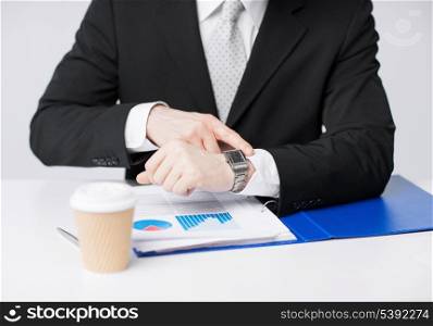 picture of businessman with graphs pointing at watch
