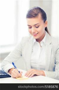 picture of businesswoman writing on sticky note. businesswoman writing on sticky note