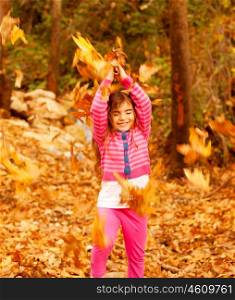Picture of cheerful little girl playing outdoors, sweet small female child throwing up dry yellow fall foliage and laughing with closed eyes, nice baby in autumn woods, carefree childhood&#xA;&#xA;