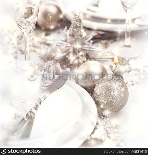 Picture of Christmastime table setting, white festive plate with knife and fork, shiny silver decoration, candle light, home interior, beautiful holiday dinnerware, romantic New Year dinner