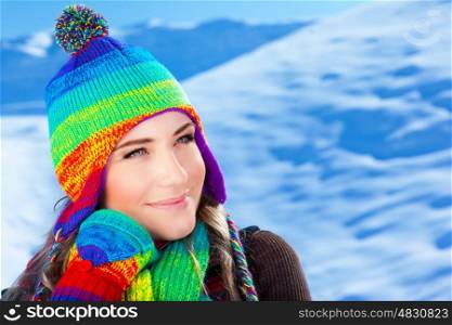 Picture of cute girl wearing colorful knitted hat with scarf and gloves on winter background, pretty teenager having fun on mountains covered snow, wintertime fashionable clothes, Christmas time&#xA;