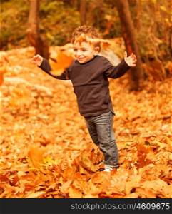 Picture of cute little boy run with raised up hands in autumnal woods, pretty small male walking in the park, cheerful infant having fun in fall forest, adorable toddler play game on backyard&#xA;&#xA;