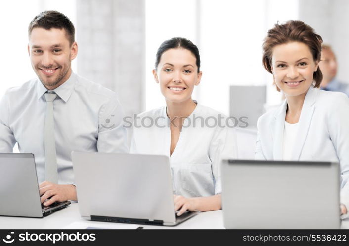 picture of group of people working with laptops in office