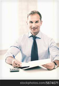 picture of handsome businessman with notebook and calculator