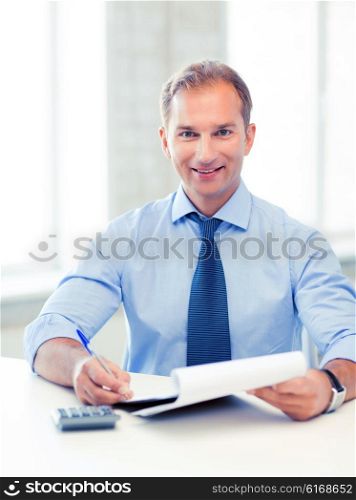 picture of handsome businessman with notebook and calculator. businessman with notebook and calculator