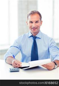 picture of handsome businessman with notebook and calculator. businessman with notebook and calculator