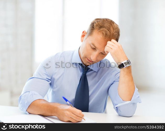 picture of handsome businessman writing in notebook