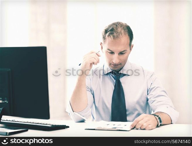 picture of handsome businessman writing in notebook