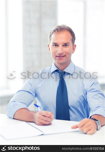 picture of handsome businessman writing in notebook. handsome businessman writing in notebook
