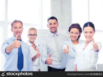 picture of happy business team showing thumbs up in office. business team showing thumbs up in office