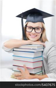 picture of happy student in graduation cap with stack of books
