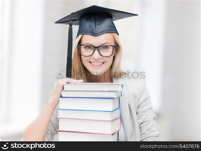 picture of happy student in graduation cap with stack of books