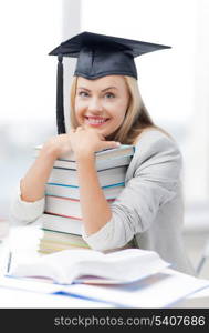 picture of happy student in graduation cap with stack of books