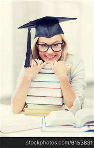 picture of happy student in graduation cap with stack of books. student in graduation cap