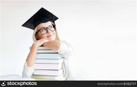 picture of happy student in graduation cap with stack of books. student in graduation cap