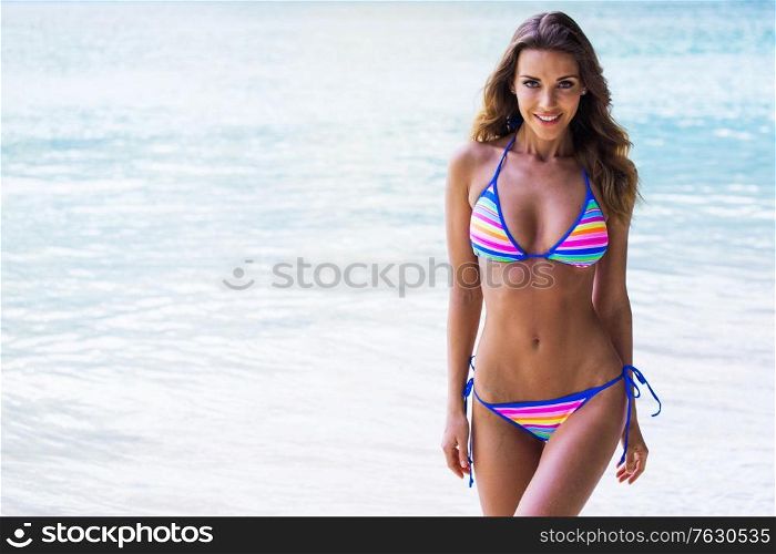 Picture of happy woman with perfect body in bikini on tropical beach, sea on background, copy space for text. Happy woman on beach