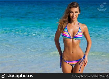 Picture of happy woman with perfect body in bikini on tropical beach, sea on background, copy space for text. Happy woman on beach